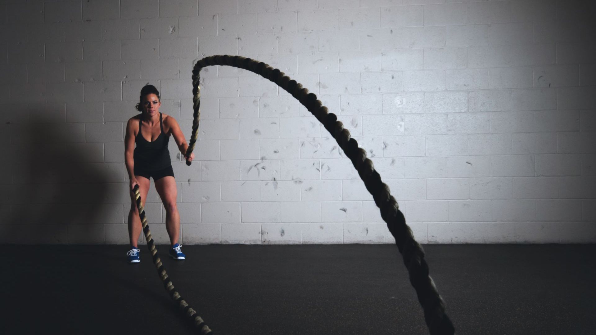 Person performing battle ropes exercise in modern industrial gym